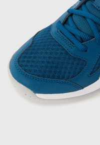 Blue athletic shoe featuring mesh upper, textured fabric, and white rubber sole. Laces and synthetic accents add detail to the design.