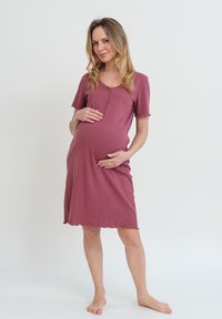 Abito premaman in un profondo mauve, a maniche corte, con collo henley e bordi ondulati, realizzato in un morbido tessuto testurizzato.
