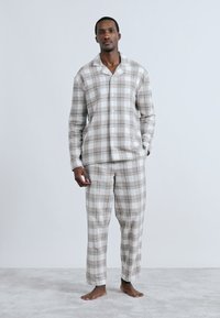 Bavlnená pyžamová súprava s károvaným vzorom v neutrálnych tónoch, obsahujúca košeľu na gombíky a nohavice s elastickým pásom, s voľným strihom a jemnou textúrou.