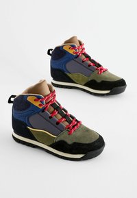 Wysokie sneakersy z mieszanką materiałów z oliwkowej zieleni, granatowego niebieskiego i szarego zamszu, czerwonymi sznurówkami oraz czarną gumową podeszwą.