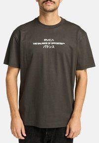 Dunkelgraues kurzärmliges T-Shirt aus Baumwolle, mit weißen Text "RVCA THE BALANCE OF OPPOSITES™" und japanischen Schriftzeichen.