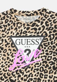 Koszulka z krótkim rękawem w panterkę z czarnym trójkątnym logo z napisem „GUESS” oraz słowem „Love” w połyskującym różowym stylu pisma.