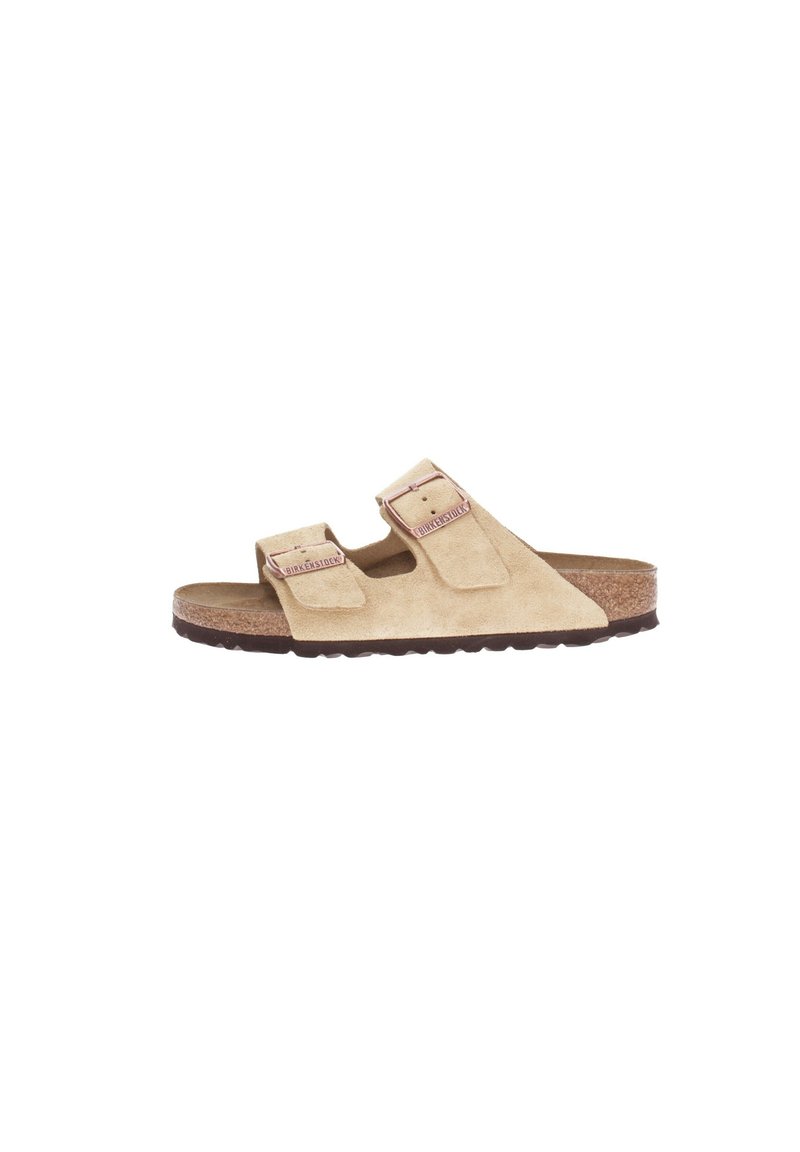 Sandalia de ante beige con dos cintas y cierres de hebilla ajustables, plantilla de corcho y suela de goma de perfil bajo. Diseño minimalista.