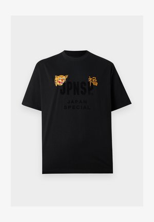T-shirt nera a maniche corte con il volto di una tigre e un carattere giapponese dorato sul petto, con il testo "JPNSP? JAPAN SPECIAL" sotto.