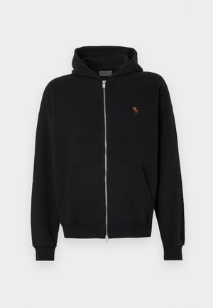 Hanorac negru cu fermoar, fabricat dintr-un material moale, având un buzunar tip cangur, mansete ribbate și un mic logo brodat pe piept.