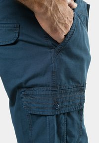Navy blue cargo shorts made of lightweight fabric, featuring side pockets, stitched detailing, and a buttoned flap on the pocket.