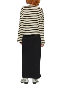 Schwarz-cream gestreiftes Longsleeve-Oberteil mit lässigem Schnitt, kombiniert mit einem schwarzen gerippten Maxirock und silbernen Stiefeletten.