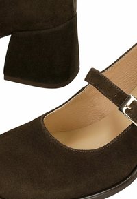 Hnědé semišové boty na podpatku s kulatou špičkou, boční přezkou a strukturovaný svrchní částí. Masivní podpatek pro stabilitu. Krémová vnitřní podšívka.