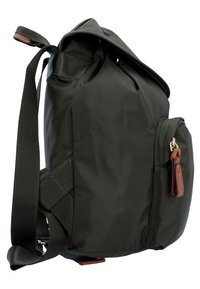 Mochila de tela negra con forma redondeada, que cuenta con un bolsillo con cremallera, correa ajustable y un acento de cuero en el tirador de la cremallera.