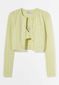 Żółty krótki kardigan z długimi rękawami i guzikami, noszony na dopasowanym żółtym dzianinowym topie bandeau.