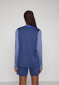 Bl�å langermet treningsgenser med lyseblå ermer og matchende shorts. Laget av glatt, lett stoff med flate sømmer og en avslappet passform.
