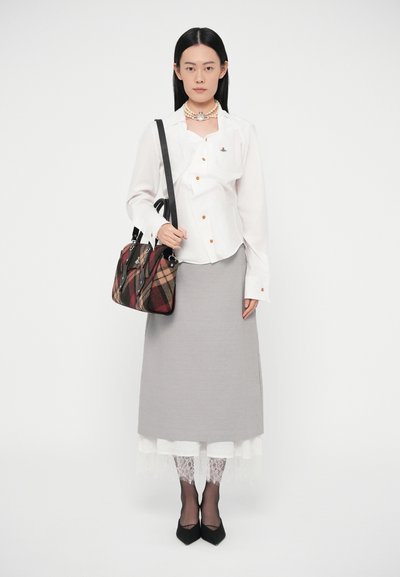 Balta pogas krekls ar oranžām pogām, pelēks svārki, melnas augstpapēžu kurpes, mežģīņu apakšsvārki un pleda soma ar melniem akcentiem.