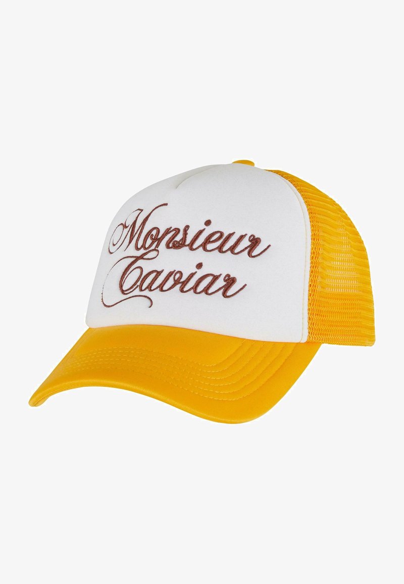 Dzeltena un balta krūšu cepure ar izliekto vizieri. Priekšējā panelī ir izšūts teksts "Monsieur Caviar" brūnā rakstā.