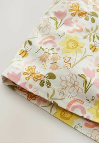 Baumwollstoff mit einem floralen Muster in Rosa-, Gelb- und Grüntönen. Auffällige Details sind Schmetterlinge und ein gestickter Saum.