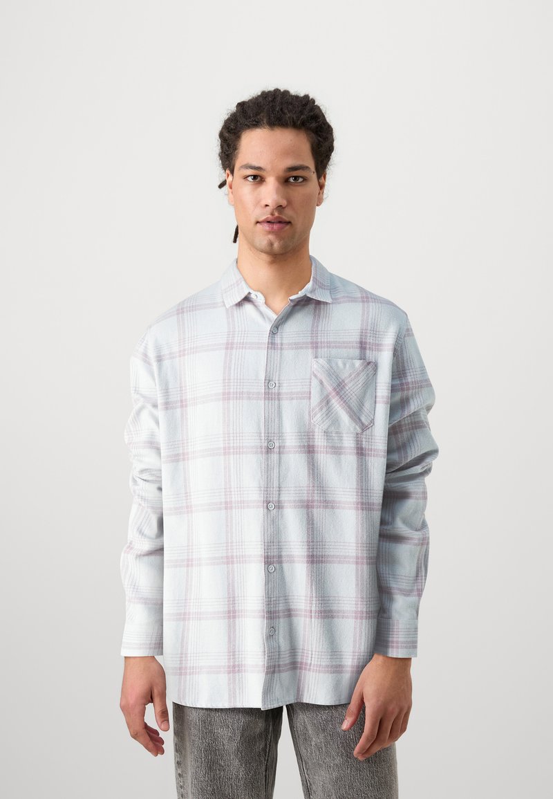 Light blue plaid shirt made of soft fabric, featuring long sleeves, a button-up front, and a single front pocket with diagonal pattern accents.