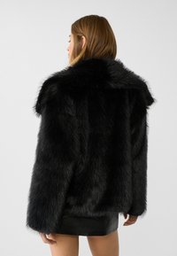 Black faux fur coat with a wide collar and long, voluminous sleeves. Features a soft texture and a loose, oversized fit.