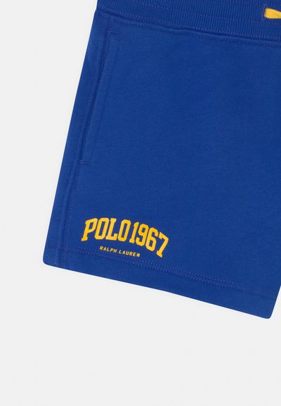 Bermudas de algodão azuis com um cós elástico, bolso lateral e texto impresso em amarelo "POLO 1967" e "RALPH LAUREN" na bainha.
