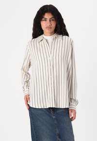 Camicia a maniche lunghe con colletto in tessuto crema con righe verticali blu, caratterizzata da una chiusura con bottoni e una vestibilità rilassata.
