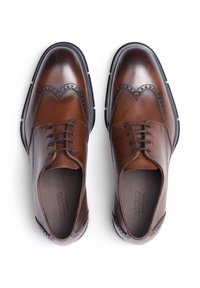Scarpe da uomo in pelle marrone con design a wingtip, caratterizzate da perforazioni dettagliate, lacci piatti e una suola nera a contrasto.