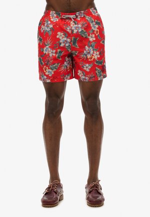 Bañadores rojos florales con cintura de cordón, patrones tropicales vibrantes y tejido ligero para mayor comodidad. Los detalles incluyen marcas visibles.