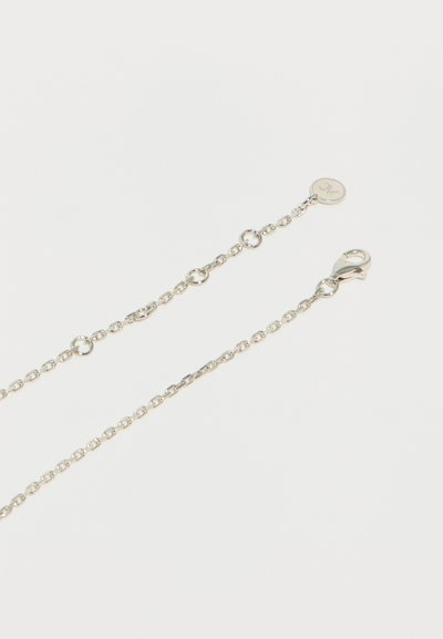 Ασημένιο κολιέ αλυσίδα με μικρούς στρογγυλούς κρίκους, κούμπωμα καβουριού στη μία άκρη και κυκλικό φυλαχτό με χαραγμένο γράμμα στην άλλη άκρη.