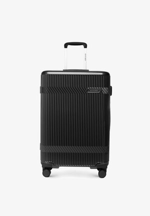 Valise rigide noire à rainures verticales, équipée de quatre roues et d'une poignée télescopique argentée, avec une plaque logo "WITTCHEN".