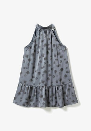 Hallituseta hall kleit kõrge kaelusega, mustade abstraktsete täppidega ja volangidega äärtega, ripub tasasele valgele taustale.