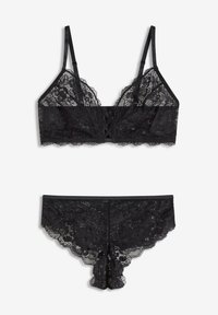 Bralette in pizzo nero con bordi ondulati e spalline regolabili, caratterizzata da un gancio frontale decorativo. Mutandine in pizzo nero coordinate con un delicato bordo.