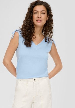 Helles blaues ärmelloses Oberteil mit V-Ausschnitt, mit Bindebändern an den Schultern, kombiniert mit weißen hochtaillierten Hosen.