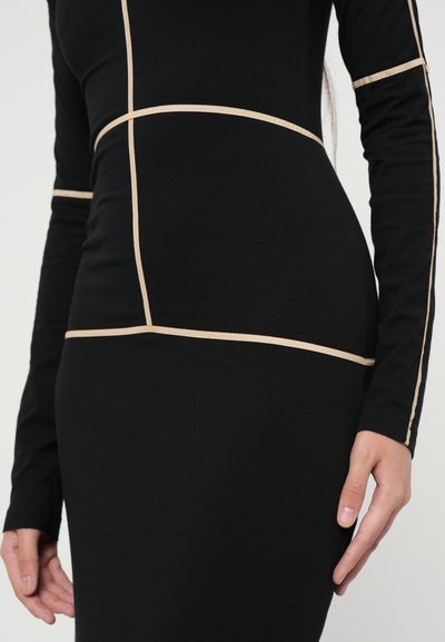 Black long-sleeve dress featuring contrasting beige seams in a grid pattern, fitted silhouette, and soft fabric texture.