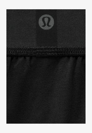 Czarna tkanina o gładkiej teksturze z marszczonym dołem i małym szarym logo. Projekt podkreśla prostotę i funkcjonalność.