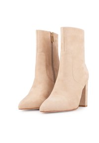 Bottines beiges en daim avec bouts pointus, couture minimaliste, et détail de fermeture éclair dorée sur le côté extérieur, avec un talon épais.