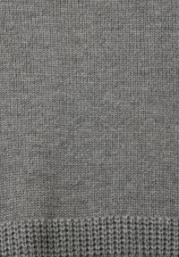 Tissu tricoté gris clair avec des motifs de mailles verticales et horizontales visibles, montrant la texture et de légères variations d'épaisseur du fil.