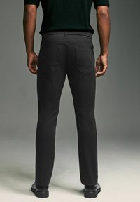 Pantaloni negri cu croi drept, dintr-un material neted, având două buzunare la spate și o baretă pentru curea. Design minimalist, fără logo de marcă vizibil.