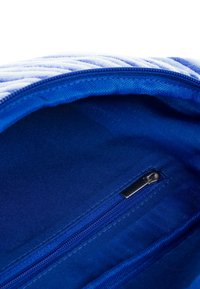 Blue fabric bag interior with smooth texture. Features a zip pocket and stitched lining. Open-top design, no visible branding details.