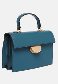 Sac à main en cuir bleu sarcelle avec une fermeture à glissière dorée, une forme structurée, une poignée supérieure et des détails d'accent en noir. Dispose d'un rabat de fermeture et d'une couture minimale.