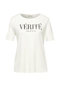 Hvid bomulds t-shirt med rund hals og korte ærmer. Fronten har sort tekst, der står "VÉRITÉ club de la rue." Blød tekstur.