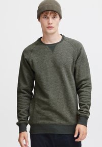 Groene sweatshirt met textuur en een ronde halslijn, voorzien van raglanmouwen en ribgebreide manchetten, gecombineerd met een bijpassende ribgebreide beanie.