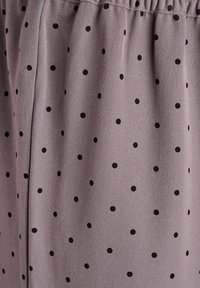 Šedá látka s malými černými puntíky, vykazující hladkou strukturu a elastický pás, vhodná pro každodenní nošení.