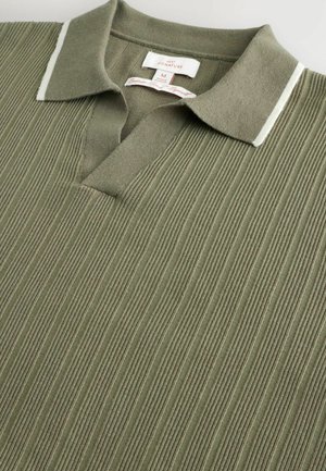 Olivgrön pikétröja med ribbad textur, vita krageförstärkningar och en placket med tre knappar. Materialet verkar mjukt och lätt.