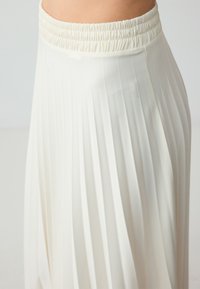 Witte plissé rok met een elastische tailleband, gemaakt van zachte stof en een vloeiende ontwerpt die beweging en comfort verbetert.