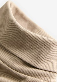 Tessuto ribbed beige con una superficie morbida e un collo cowl piegato, caratterizzato da righe verticali e una finitura liscia.