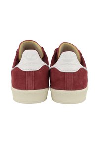 Sneakers in suede rosso con accenti in pelle bianca e suola in gomma testurizzata. Presentano cuciture visibili e un logo sulla linguetta del tallone.