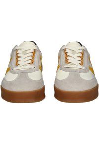 Sneaker con upper in suede beige, dettagli in pelle crema, strisce laterali gialle e suole in gomma marrone. Presentano lacci bianchi e linguetta imbottita.