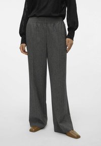 Grå vida byxor med elastisk midja, gjorda av ett strukturert tyg. Kombination med bruna slip-on skor.