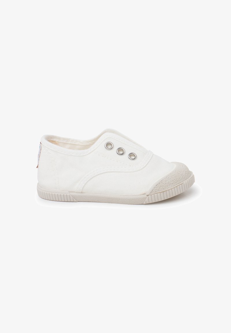 Chaussure blanche basse en toile sans lacets avec trois œillets en métal et embout ainsi que semelle en caoutchouc texturé, vue de côté sur fond blanc.
