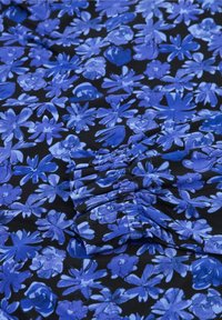 Stoff mit einem floralen Muster, das verschiedene Blautöne von Blumen auf schwarzem Hintergrund zeigt, mit gerafften Details für Textur.