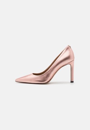 Glänzender metallischer rosegoldener High-Heel-Pumps mit spitz zulaufender Zehenpartie und schlankem Absatz, seitlich auf einem einfarbigen hellgrauen Hintergrund dargestellt.
