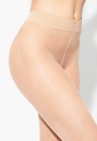 Collant trasparenti nudi con una texture morbida, dotati di una cintura larga e flessibile con un logo del marchio discreto. Progettati per una vestibilità impeccabile.