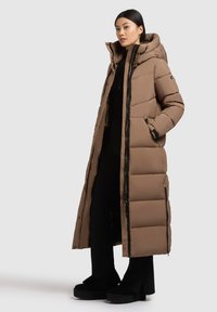 Abrigo largo acolchado marrón con capucha, cremallera frontal, bolsillos laterales y puños acanalados. Textura lisa con un ligero brillo.